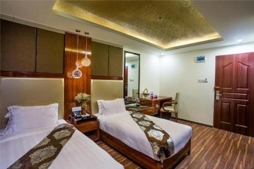 a hotel room with two beds and a desk at Hotel Noorjahan Grand in Sylhet