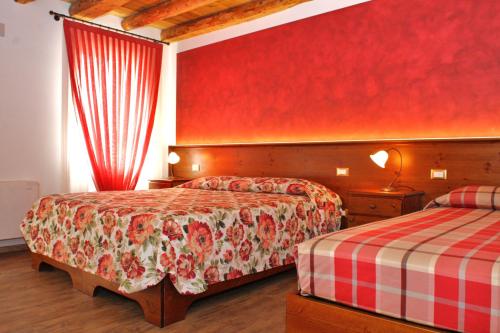 a hotel room with two beds and a red wall at Al Filò in Marostica