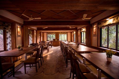 a row of tables and chairs in a room with windows at Kaular Atithis Grand Kokan Resort in Ganpatipule