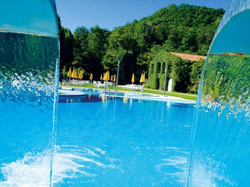 a large blue swimming pool with a fountain at Terme Preistoriche Resort & Spa in Montegrotto Terme