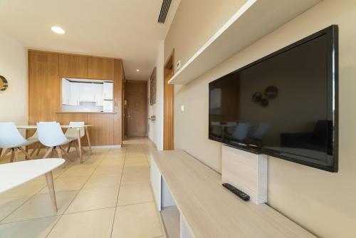 sala de estar con TV de pantalla plana grande en la pared en Apartamentos Costa Luz Punta Umbría, en Punta Umbría