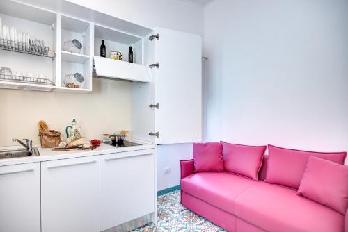 a living room with a pink couch and a kitchen at Oleum in Massa Lubrense