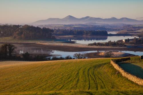 a field with a river and mountains in the background at Dufferin Coaching Inn in Killyleagh