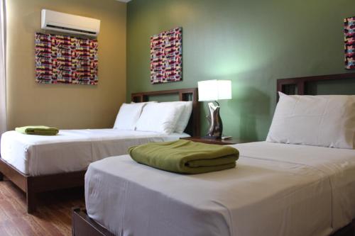 een hotelkamer met 2 bedden met witte lakens bij Purple Tree Bed & Breakfast in Manilla