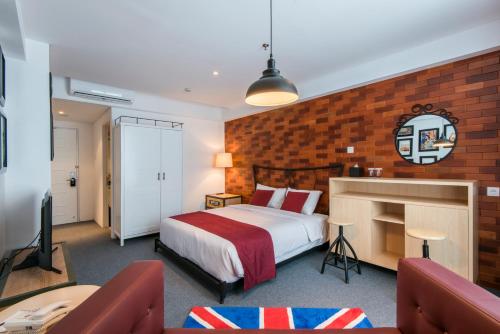 a bedroom with a bed and a brick wall at Yan's House Hotel in Kuta