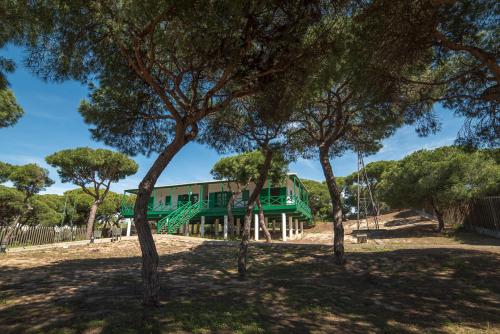 a green building with trees in front of it at Apartamentos Costa Luz Punta Umbría in Punta Umbría
