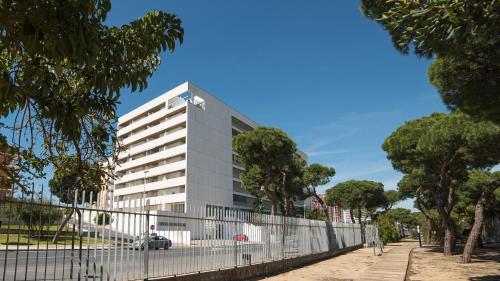 a white building with a fence in front of it at Apartamentos Costa Luz Punta Umbría in Punta Umbría