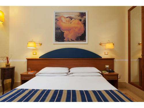 a bedroom with a bed and a painting on the wall at Hotel Kennedy in Rome