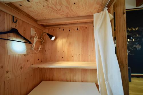a small room with a bed and a curtain at Saga International Guesthouse Hagakure in Saga