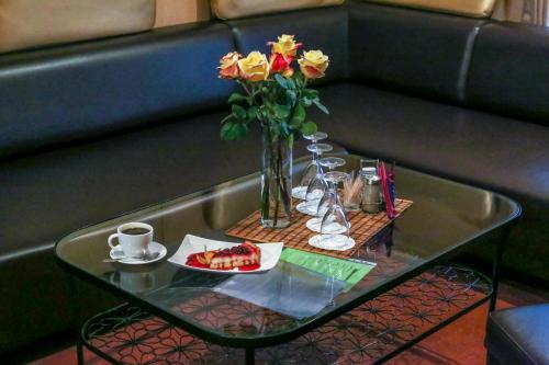 a table with a plate of fruit and a vase with flowers at Domino Hotel in Nizhny Novgorod