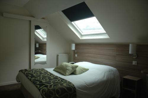 a bedroom with a large bed with a skylight at Logis Hotel Le Chêne Vert in Savenay