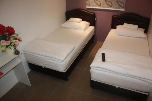 two twin beds in a room with a vase of flowers at M Design Hotel @ Pandan Indah in Kuala Lumpur