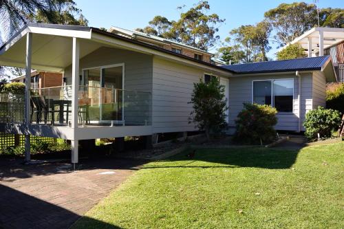 a house with a balcony and a yard at Dungowan Holiday Accommodation in Erowal Bay
