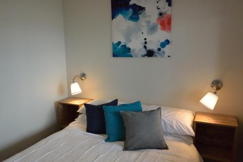 a bedroom with a bed with blue pillows and two lights at Dungowan Holiday Accommodation in Erowal Bay