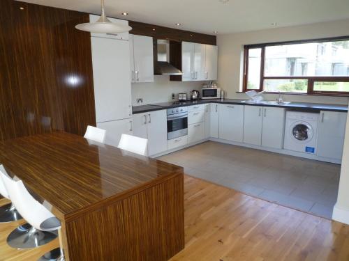 a kitchen with a wooden table and white cabinets at Castlemartyr Holiday Lodges 2 Bed by Trident Holiday Homes in Castlemartyr