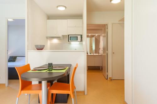 une cuisine et une salle à manger avec une table et des chaises dans l'établissement City Résidence Lyon Marcy, à Marcy-lʼÉtoile