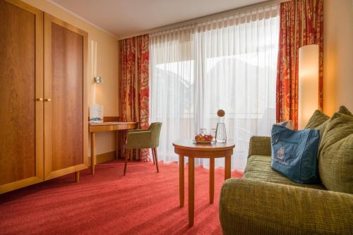 a hotel room with a couch and a table and a window at Vivea Hotel Umhausen im Ötztal in Umhausen