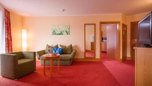 a living room with a couch and a table and a television at Vivea Hotel Umhausen im Ötztal in Umhausen
