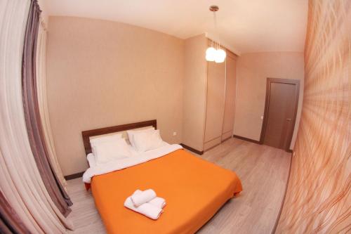 a bedroom with an orange bed with two white towels on it at 310 Уютные дизайнерские апартаменты в отличном районе Идеально для командированных и туристов in Almaty