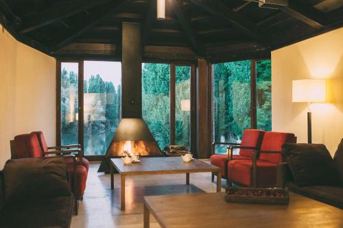 a living room with a fireplace and red chairs at Fuente Aceña Hotel Boutique in Quintanilla de Onésimo