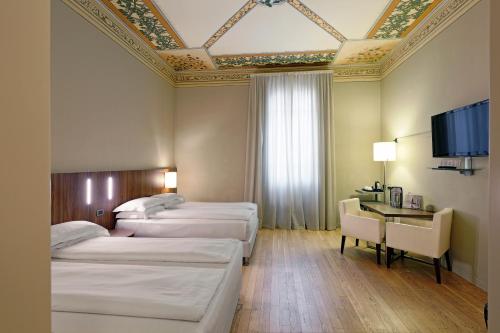 ボローニャにあるイ ポルティーチ ホテル ボローニャのベッド3台、薄型テレビが備わるホテルルームです。