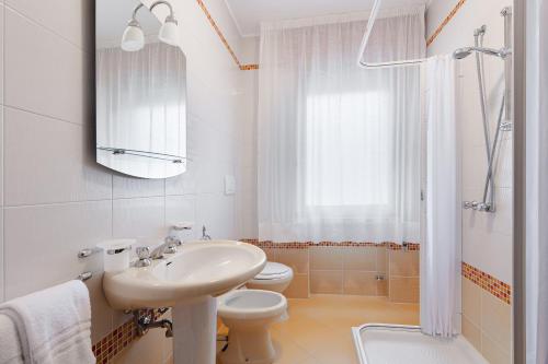 a white bathroom with a sink and a toilet at Residence Eur in Sottomarina