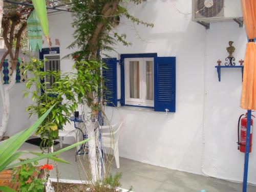 a white wall with blue shutters and a window at Boussetil Rooms CapAnMat in Tinos Town