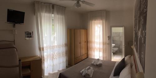 a bedroom with a bed and a television and curtains at Hotel Monti in Riccione
