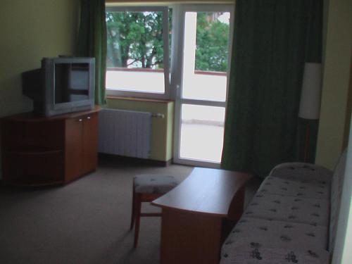 a living room with a tv and a chair and a table at Hotel Seasons in Tryavna