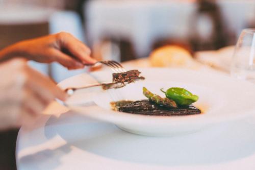 a person eating a plate of food with a fork at Fuente Aceña Hotel Boutique in Quintanilla de Onésimo