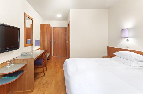 1 dormitorio con 1 cama, escritorio y TV en Hérað - Berjaya Iceland Hotels, en Egilsstadir