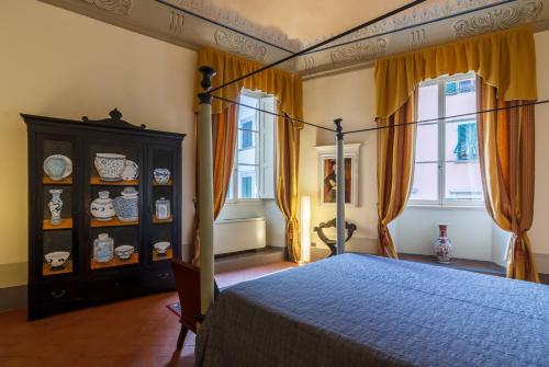 een slaapkamer met een bed, een dressoir en ramen bij Dimora Storica Palazzo Puccini in Pistoia