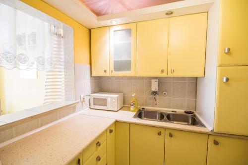 cocina con armarios amarillos, fregadero y microondas en Apartamenty Zabrze, en Zabrze