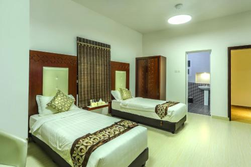 a hotel room with two beds and a bathroom at Zaki Hotel Apartment in Sur