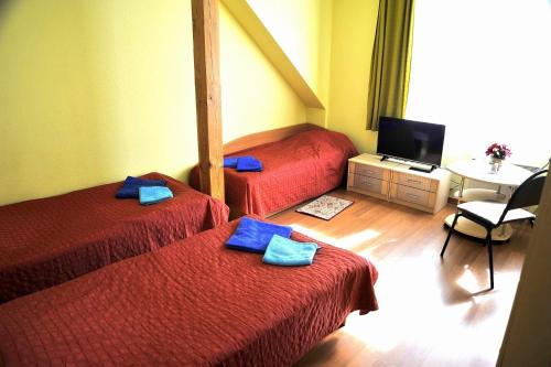 a room with two beds and a table with a tv at Pakrantė in Klaipėda