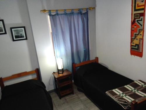 two beds in a small room with a window at Hostal Namaste in Salta