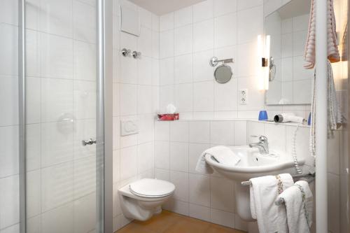 a white bathroom with a toilet and a sink at Gasthaus Sonne Neuhäusle in Sankt Märgen