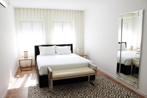 a bedroom with a large white bed and a mirror at Bracara Guest House "Bom Jesus" in Braga