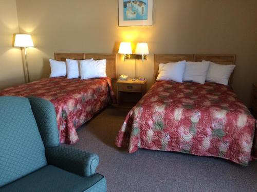 una habitación de hotel con 2 camas y una silla en Haven Inn, en St. Anthony
