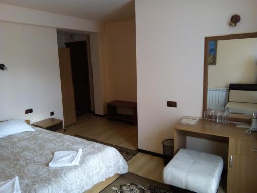 a bedroom with a bed and a desk and a mirror at Panorama Family Hotel in Zlatograd