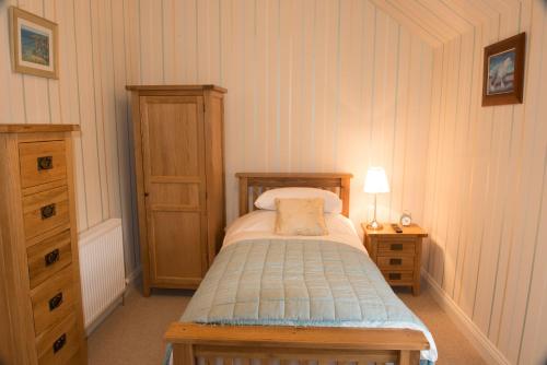 a small bedroom with a bed and a dresser at Bishopcleugh Guest House in Lockerbie