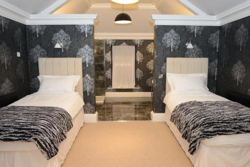 two beds in a room with black and white wallpaper at Bishopcleugh Guest House in Lockerbie