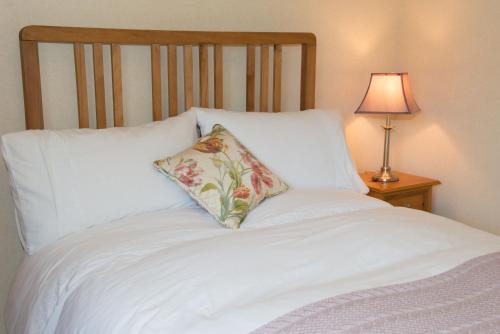 a white bed with a pillow on it with a lamp at Bishopcleugh Guest House in Lockerbie