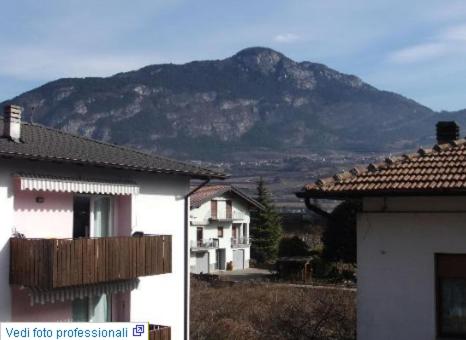 a mountain in the distance with a house and a building at Hotel Vela in Trento