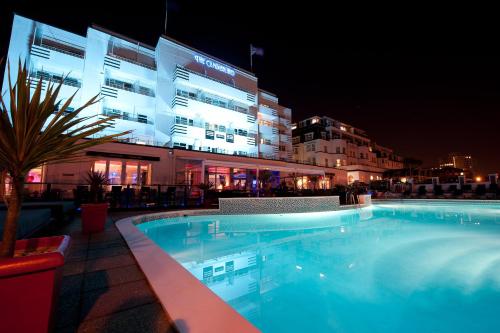 uma piscina em frente a um edifício à noite em Cumberland Hotel - OCEANA COLLECTION em Bournemouth