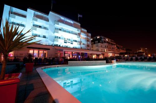 a swimming pool in front of a building at night at Cumberland Hotel - OCEANA COLLECTION in Bournemouth