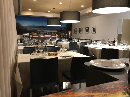 a restaurant with white tables and chairs and a man in the background at Bis Hotel Varese in Varese