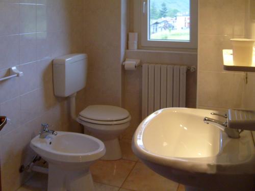 een badkamer met een wit toilet en een wastafel bij Hotel Ristorante Sasso Remenno in Val Masino