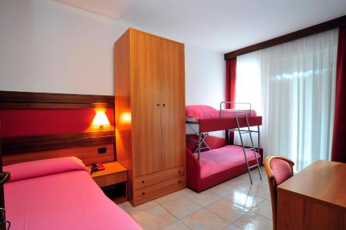 una camera con un letto rosso, un letto a castello e una scrivania di Hotel Ristorante Sasso Remenno a Val Masino