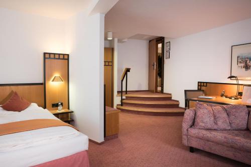 a hotel room with a bed and a couch and stairs at Hotel Schere in Northeim